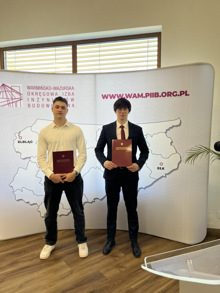 Na zdjęciu widzimy po lewej stronie Emila Chełstowskiego 4b1 oraz Michał Kalinowski 5bg stojących obok siebie na tle ścianki Warmińsko-Mazurskiej Okręgowej Izby Inżynierów Budownictwa.