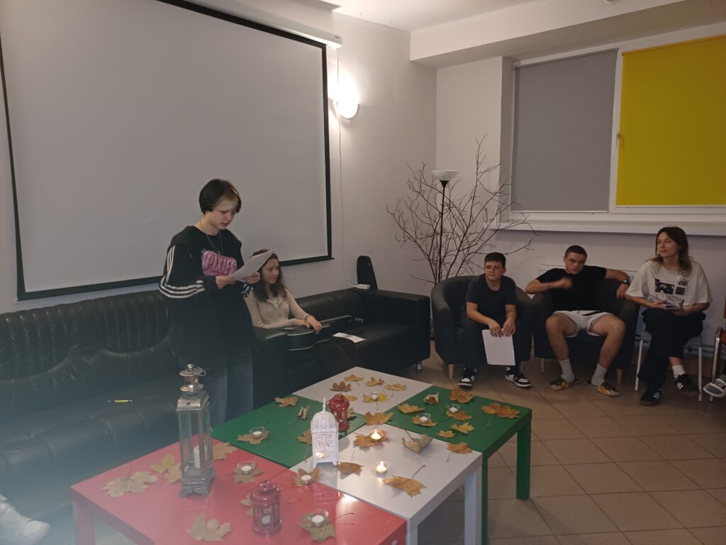 4- Na zdjęciu widać grupę młodych osób spędzających wspólnie wieczór w bursie – zaduszki poetyckie. Pomieszczenie zostało nastrojowo udekorowane, co wprowadziło ciepły, melancholijny klimat. Uczestnicy usiedli na kanapach i krzesłach, tworząc kameralną atmosferę sprzyjającą refleksji. Wychowankowie przygotowali recytacje wierszy i piosenki.