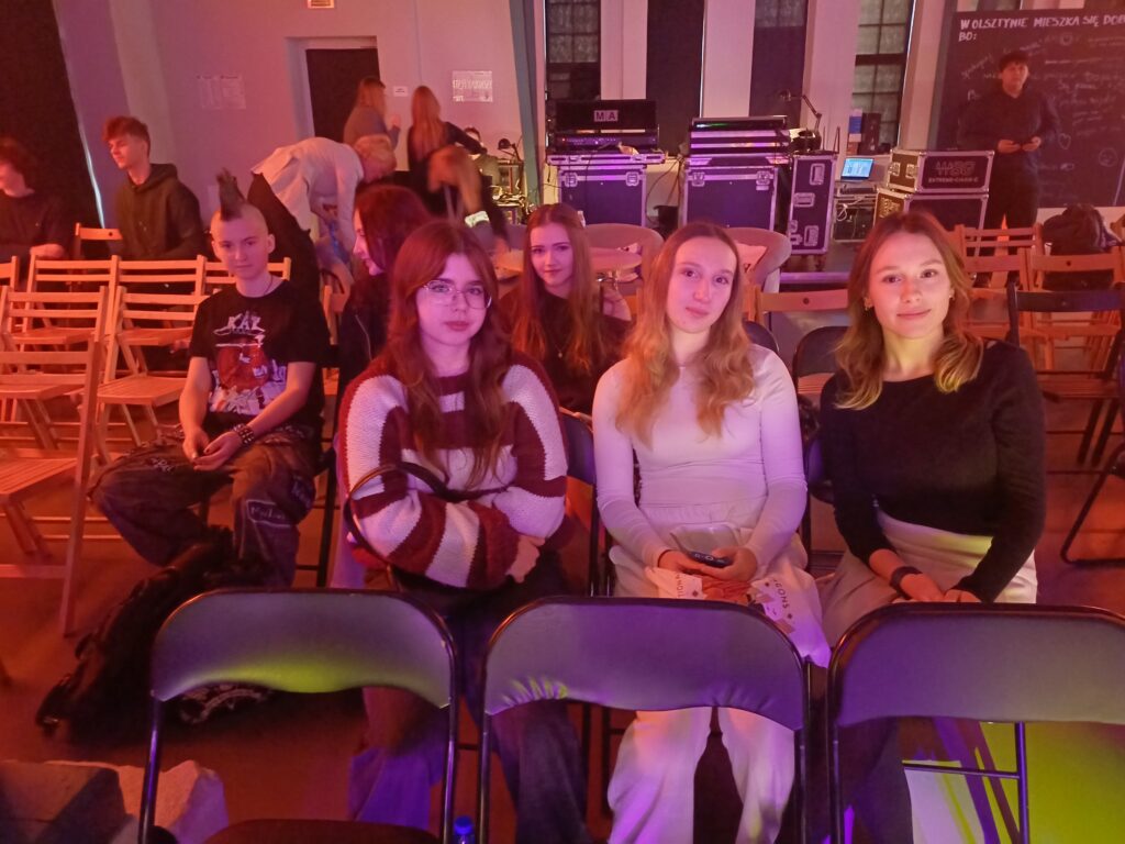 2 – Dziewczęta z bursy podczas festiwalu piosenki, w oczekiwaniu na swoje występy. W atmosferze skupienia i radosnego podekscytowania, wspierają się nawzajem i przygotowują do prezentacji swoich talentów.