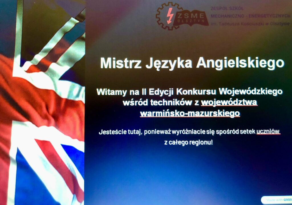 „Slajd powitalny konkursu Mistrz Języka Angielskiego, z logo szkoły w górnej części ekranu, tekstem informacyjnym na czarnym tle oraz fragmentem flagi Wielkiej Brytanii po lewej stronie.”
